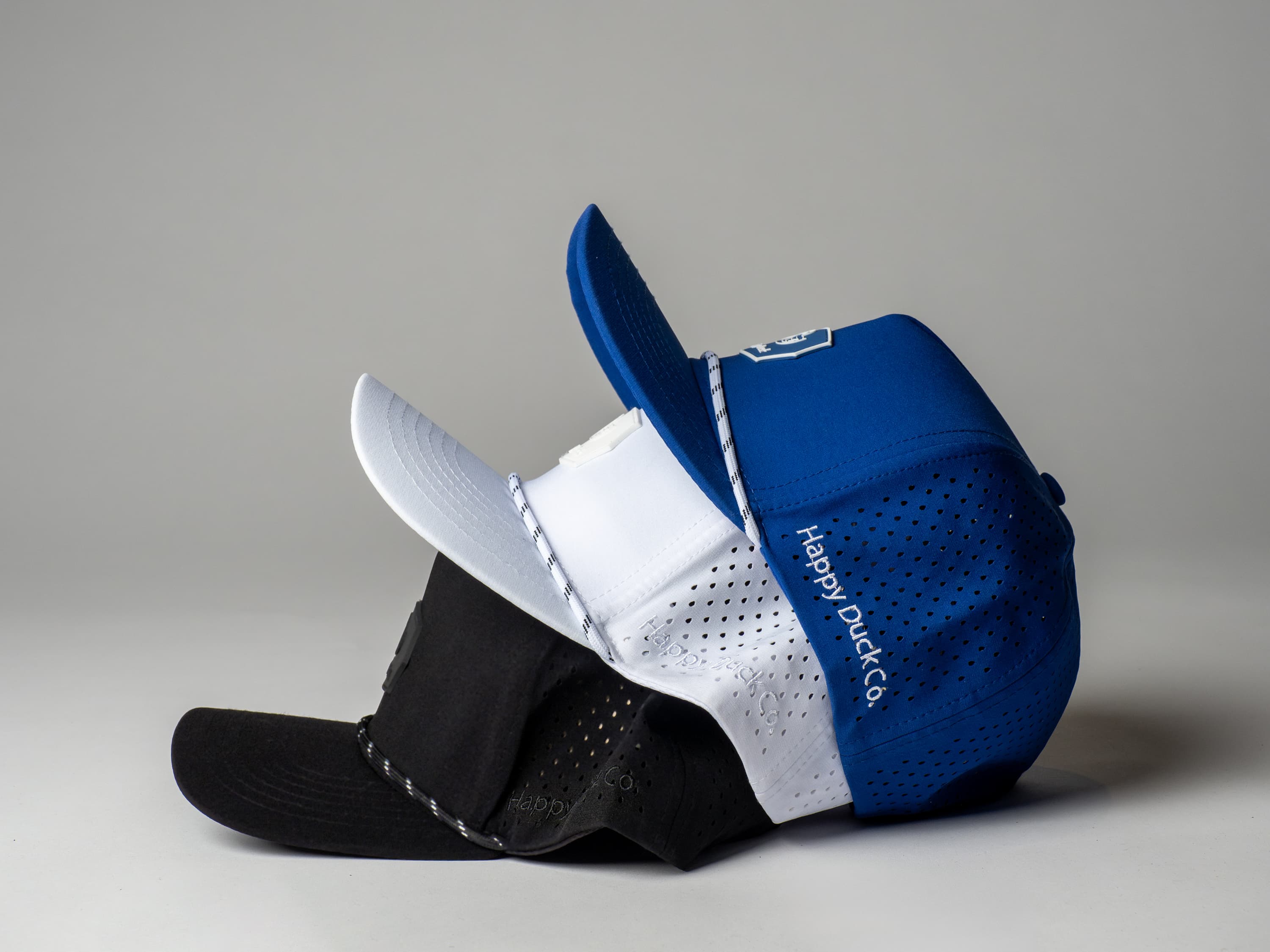 Happy Duck caps stacked, showing the woven rope-trim brim detail